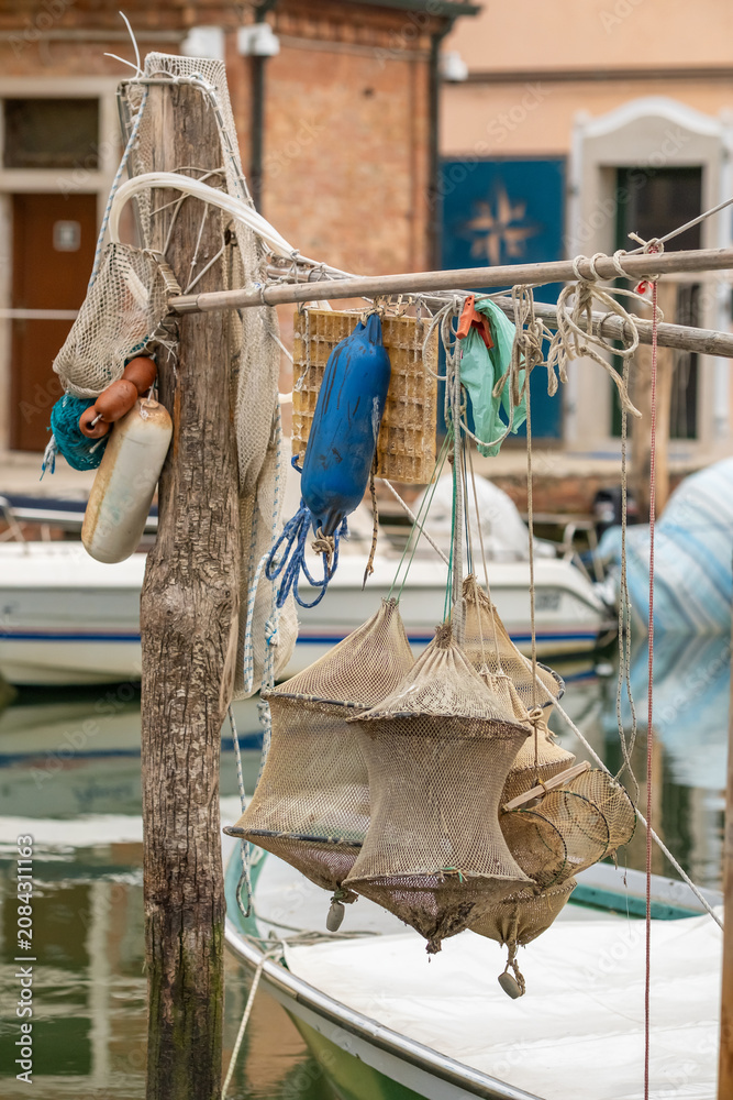 Fototapeta premium Traditional fishing nets and blue buoys hanging in a harbor, Chioggia, Italy