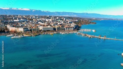 Aerial view of the Geneva waterfront along Quai du Mont Blanc on Lake Geneva, Switzerland, with hotels, a paddle steamer, the Paquis pier and snow capped Jura mountains on a clear winter day.