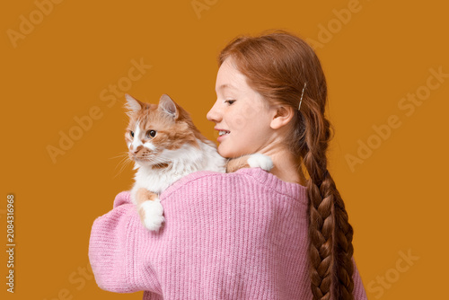 Redhead teenage girl with cute cat on orange background, back view