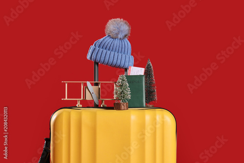 Suitcase with Christmas and travel accessories on red background. Closeup