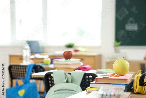 Billede på lærred Apple with books on desk in classroom, closeup