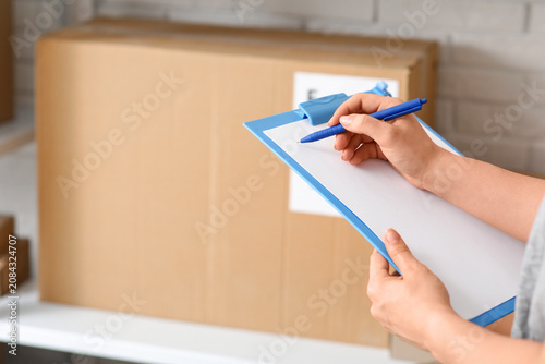 Woman writing in clipboard ...