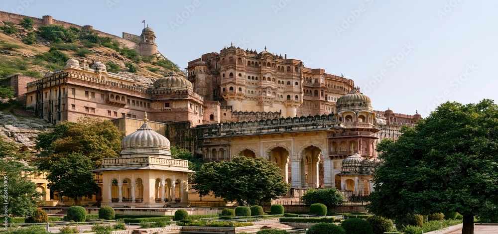 Fototapeta premium An ancient Indian royal palace stands with vibrant colors and detailed architecture under a clear blue sky.