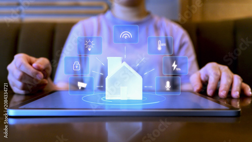 Foto A person using a tablet to control a smart home system with digital hologram icons for lighting, security, energy, and IoT connectivity, representing modern home automation technology