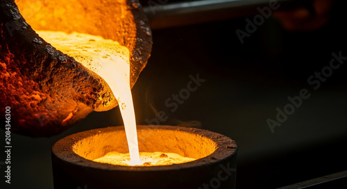 Molten metal pouring from a crucible into a mold, representing creation, transformation, and industrial process, showcasing raw material in intense heat