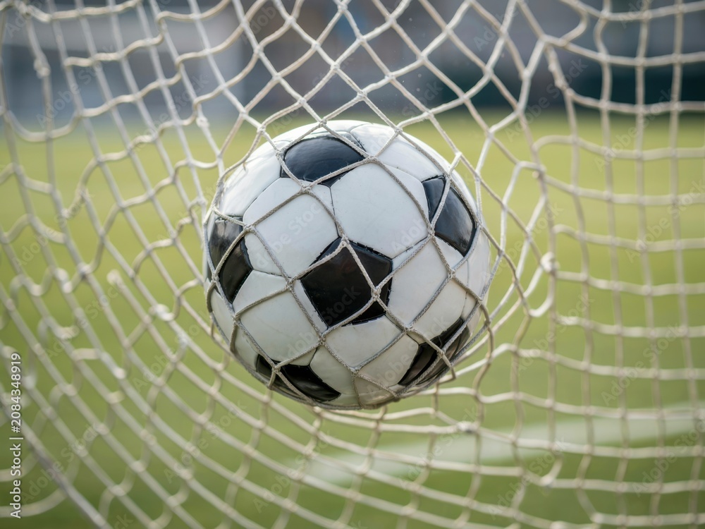Fototapeta premium Black and white soccer ball stopped near goal net