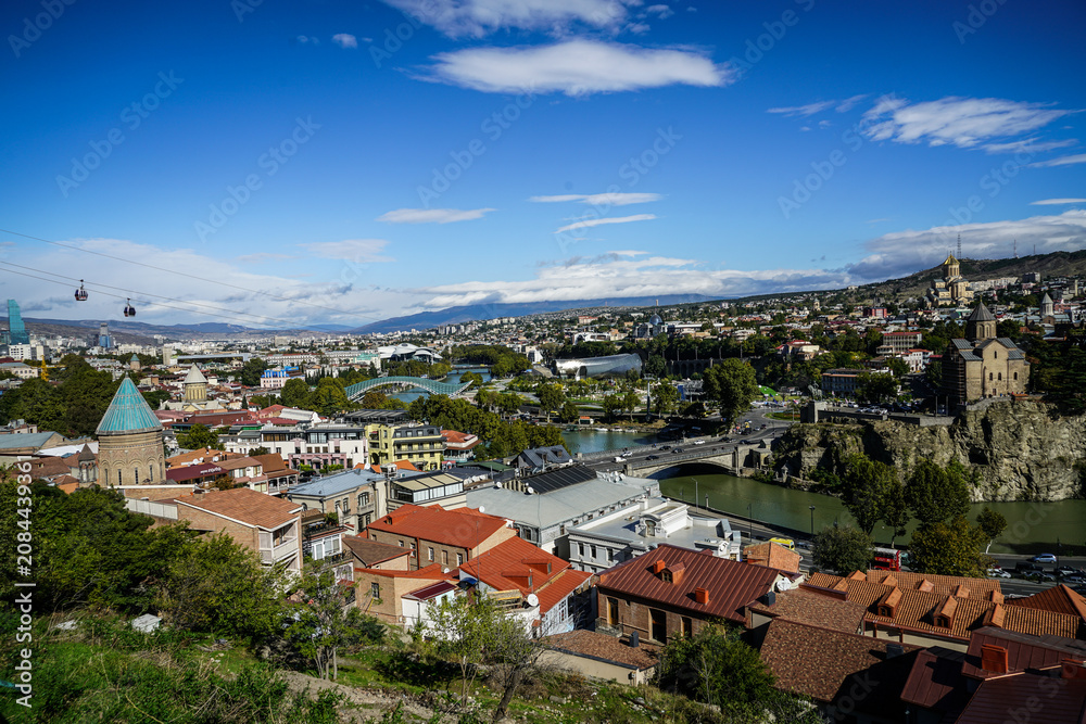 Fototapeta premium Scenic elevated view of Tbilisi, Georgia, highlighting Metekhi Church, Mtkvari River, and the iconic Peace Bridge.