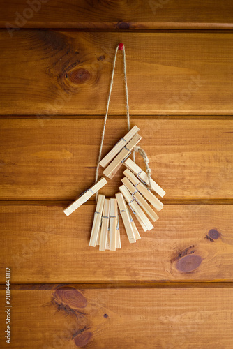 Clothespins hang on a string on a wooden wall in a simple indoor setting during the daytime