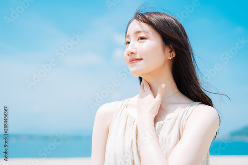 海で日焼け止めを塗る若い女性
