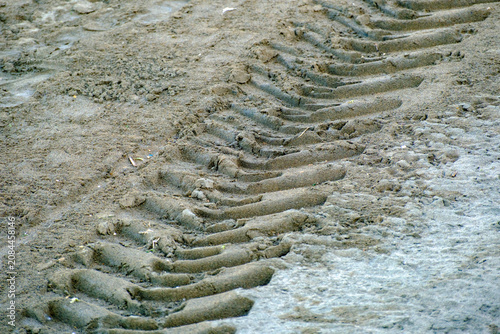 Canvastavla Deep heavy tire tracks and aggressive tread marks heavily impressed into the wet gray coastal beach sand signifying human mechanical intrusion into the peaceful natural environment
