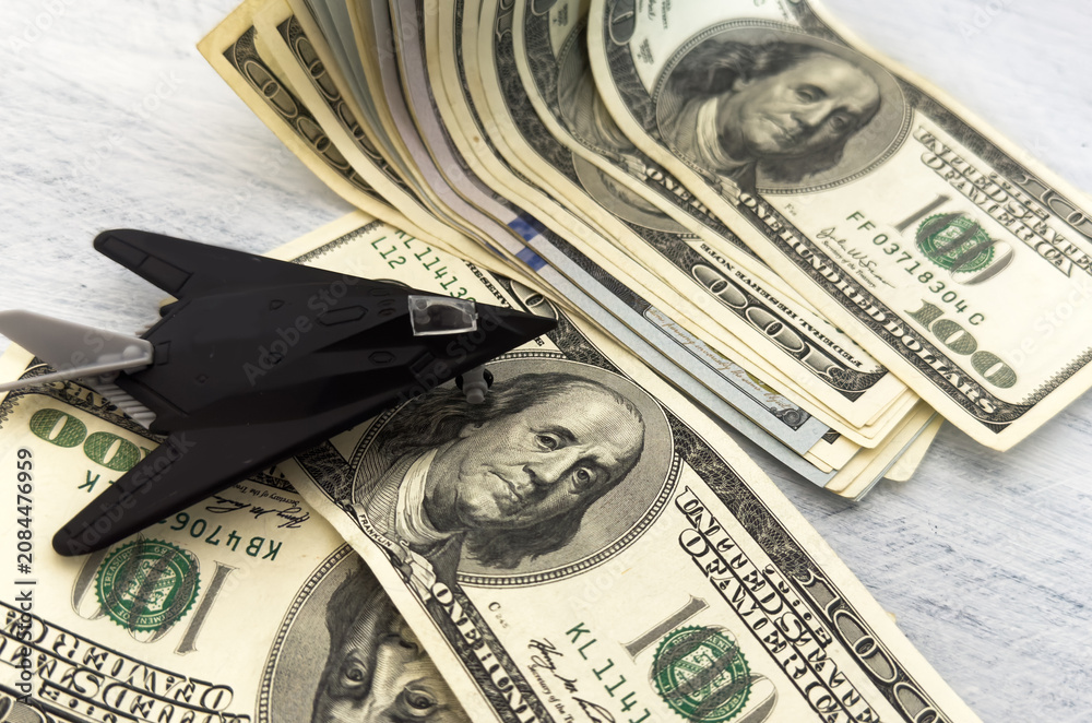 Fototapeta premium military miniature toy airplane on dollars background