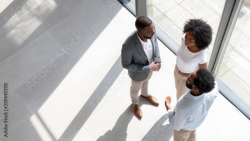 Business professionals collaborating discussing project details with mobile phones modern office space