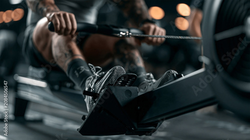 HYROX style cardio training, athlete using rowing machine during intense endurance workout.	
