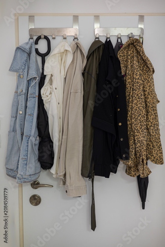 Фотография Casual clothes and accessories hanging on a door coat rack in a hallway