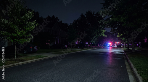 Police Patrol Car and Emergency Vehicles with Flashing Lights in Night Neighborhood