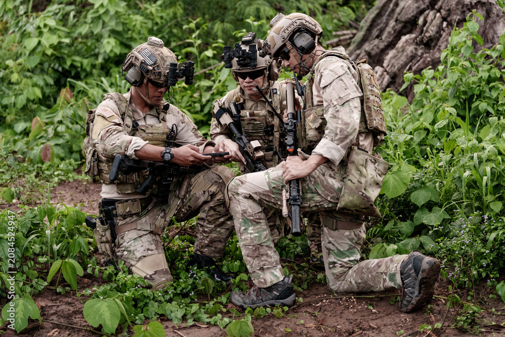 Fototapeta premium Soldiers review plans in a forest while preparing for a mission during day time