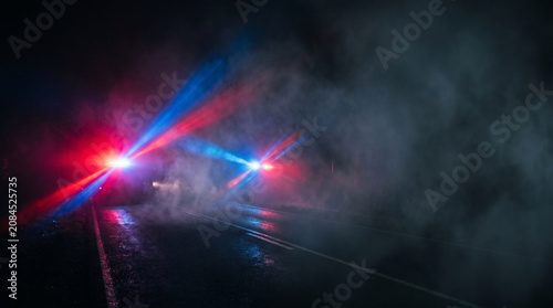 Red and Blue Emergency Vehicle Lights Shining Through Thick Fog on Dark Road