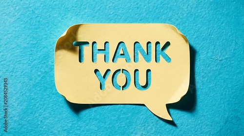 A vibrant yellow paper cutout speech bubble displaying 'THANK YOU' text, symbolizing deep gratitude and heartfelt appreciation on a striking blue background
