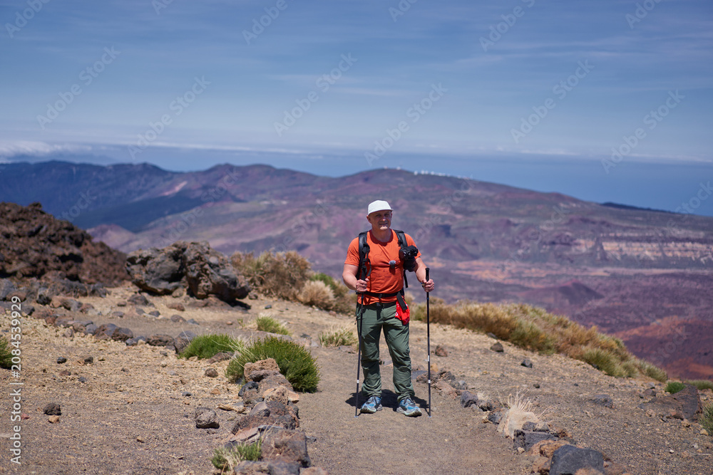 Fototapeta premium Hiker with trekking poles on mountain trail