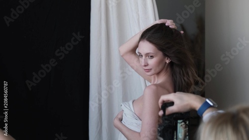 Portrait of a beautiful brunette with long hair on a fabric background in the studio. Beautiful natural woman posing for the camera