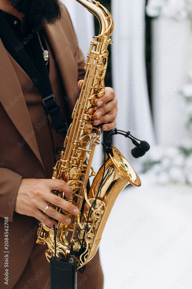 Obraz premium Musician playing golden saxophone with wireless microphone