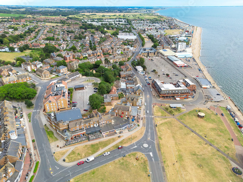 Dramatic drone view of the famous seaside town of Hunstanton, Norfolk, UK. Showing distance arcades and a fun fair along the beach coastline. Nearby the town centre and green space, seen in summer.