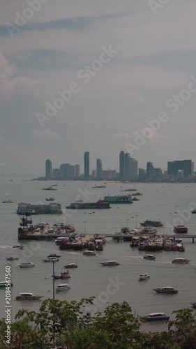 Wide panoramic Pattaya Bay in Thailand featuring numerous anchored boats, turquoise sea, and the modern city skyline in the background during daytime. 