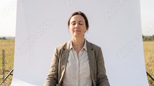Woman in business attire meditating outdoors with eyes closed