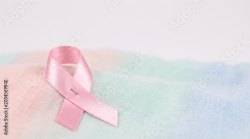 Pink ribbon symbol for breast cancer awareness on soft pastel fabric background