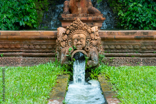 Traditional Balinese stone water fountain statue in a lush tropical garden