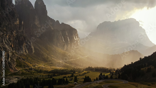 фотографія Dolomites mountains winding road sunlight filtering through clouds