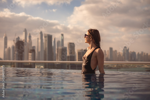 Woman enjoying infinity pool with dubai skyline view