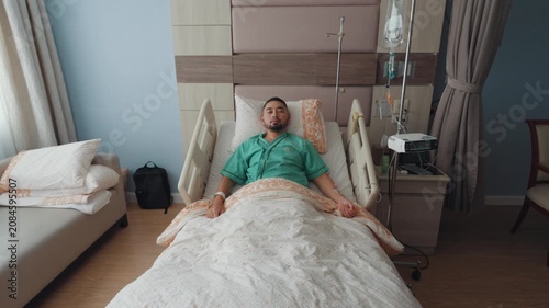 Male patient resting and recovering in a modern hospital room with IV drip, medical bed, and healthcare equipment, representing treatment, recovery, and medical care.