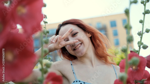 Young girl smiling, breathing, relaxing against the background of pink blooming mallow flowers, allergy health concept: spring, blooming flowers, allergy, health