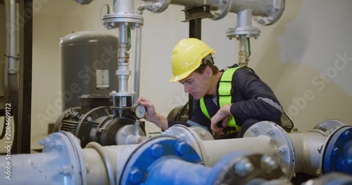 An engineer performs a diagnostic check on an industrial pump system, carefully monitoring the pressure gauge to ensure operational safety and efficiency.