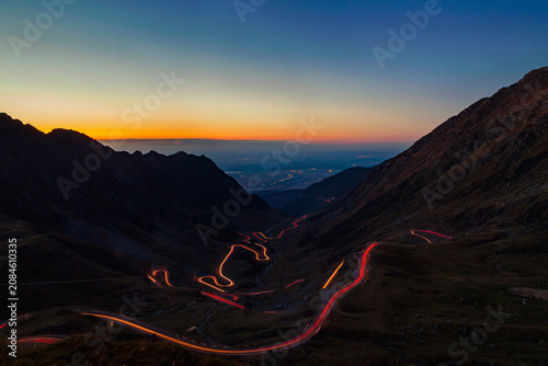Transfagarasan road winding through mountains at dusk with light trails