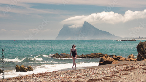Woman walking on beach with rock of gibraltar in background