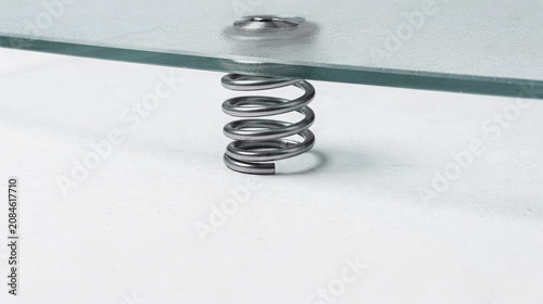 Metal spring under glass plate pressure