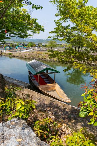 Принти на полотні Traditional wooden riverboat moored along a peaceful riverside surrounded by lus