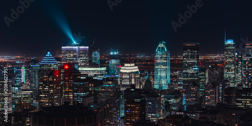 Montreal downtown skyline illuminated at night with glowing skyscrapers and a bright light beam over the financial district, Quebec, Canada