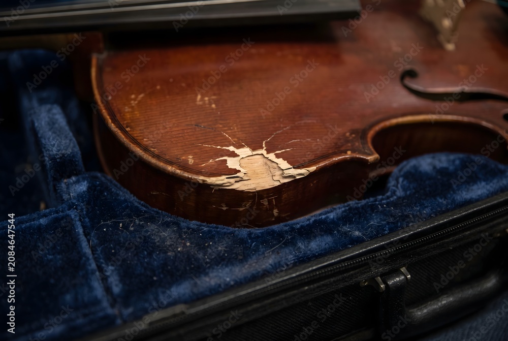 Obraz premium Close up of an impact dent and chipped varnish on the wooden surface of a violin inside a case