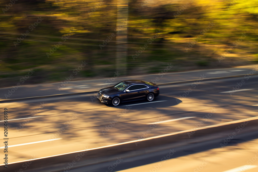 Obraz premium Dark car driving fast on highway road