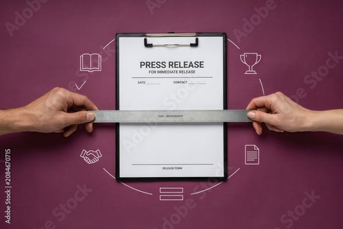 Two hands pulling a clipboard with a press release on a purple background with icons