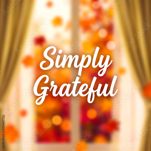 Simply grateful text overlay on a blurred autumn window background with warm bokeh lights and falling leaves