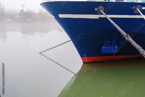 фотографія The bow of a blue ship with a white stripe, blue anchor pocket, and red waterlin