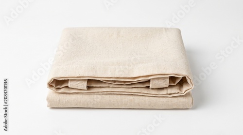 Folded beige linen napkin, stacked tablecloth, cotton fabric