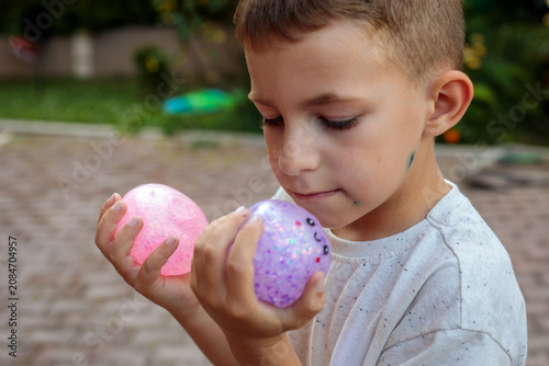 Fotografía Smiling little boy playing with a glittery dumpling shaped squishy toy outdoors,