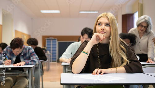 Fotografie Young woman student concentrating and thinking during a school exam with other s