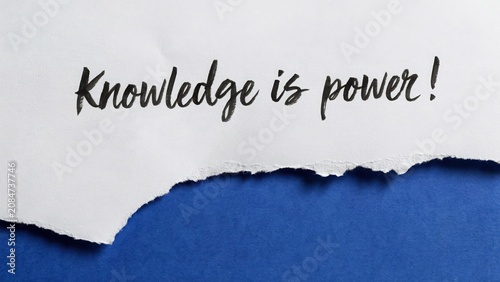 Calligraphy text knowledge is power written on torn white paper against blue background symbolizing education and wisdom.