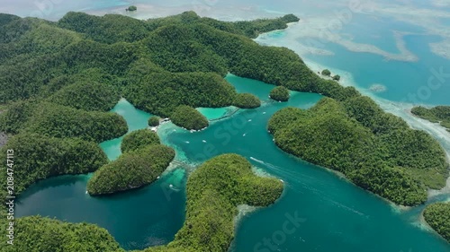 Cluster of green islets with turquoise lagoons dotted with moving boats. Sugba Blue Lagoon. Siargao, Philippines.